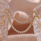 Gold hoop earrings with clear gemstones on a decorative stand.