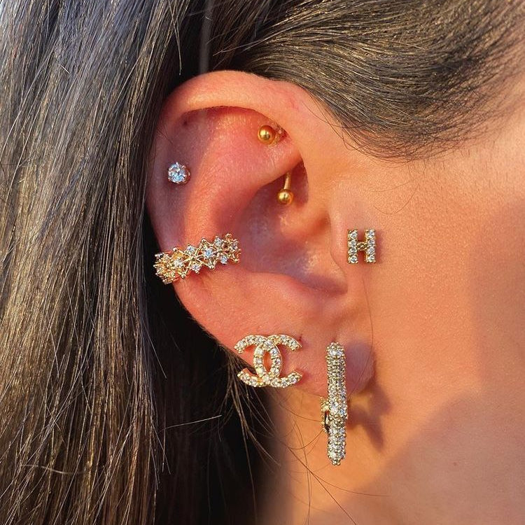 Close-up of an ear with multiple gold and diamond earrings.