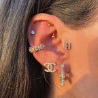 Close-up of an ear with multiple gold and diamond earrings.