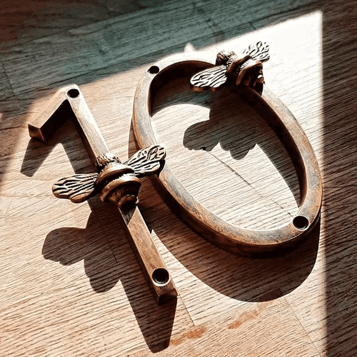 Decorative metal number '13' with bee designs on a wooden surface