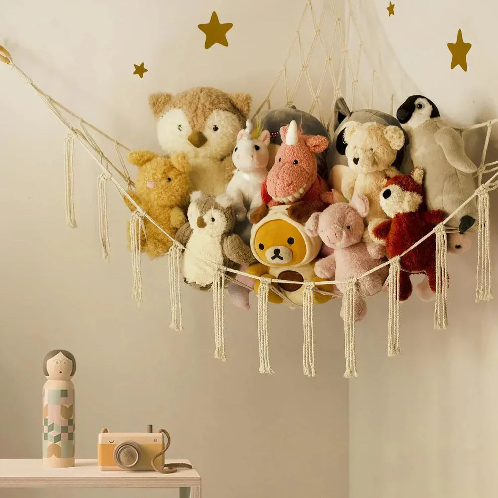 Collection of stuffed animals hanging on a string with decorative stars on a light-colored wall.