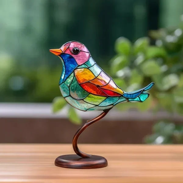 Colorful stained glass bird sculpture on a wooden stand with a blurred green background