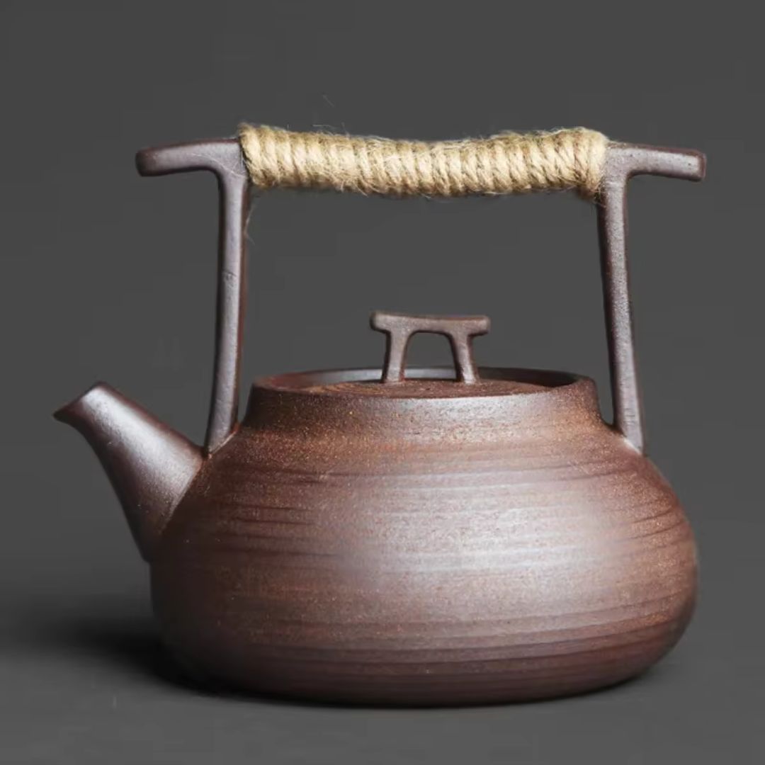 Brown ceramic teapot with rope handle on a dark gray background