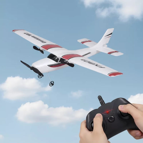 White and red remote control airplane flying in the sky with a person holding a controller.