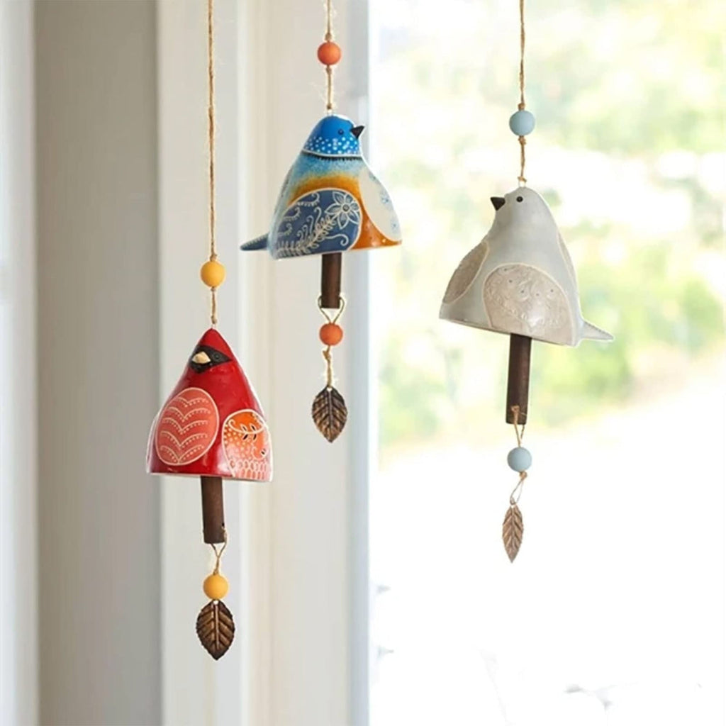 Colorful ceramic bird-shaped wind chimes hanging against a window.