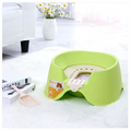 Green pet litter pan on a white carpet with a couch and flowers in the background