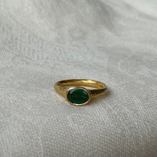 22ct Gold ring with a emerald gemstone on a light gray fabric background