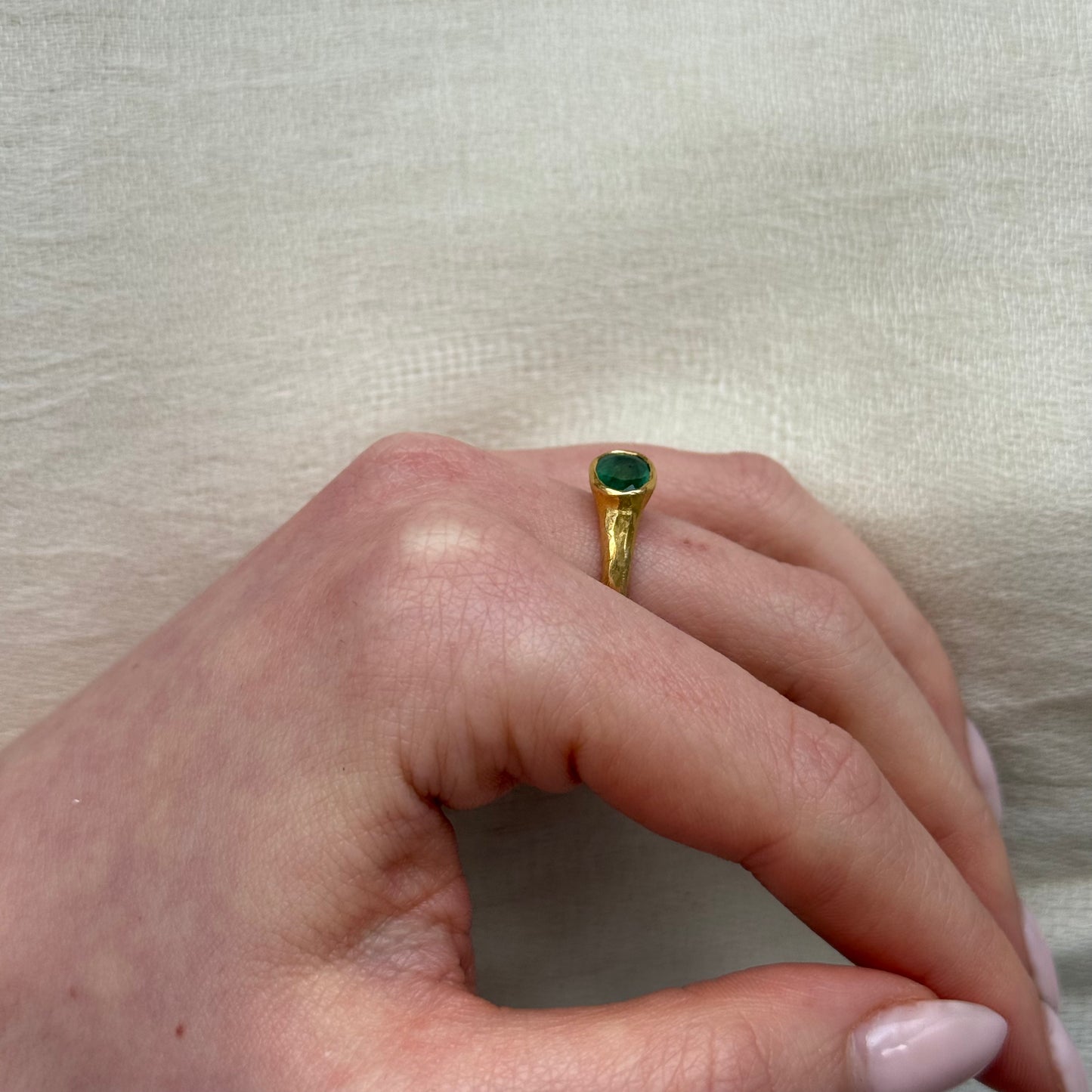 22ct Gold ring with a green emerald on a neutral background