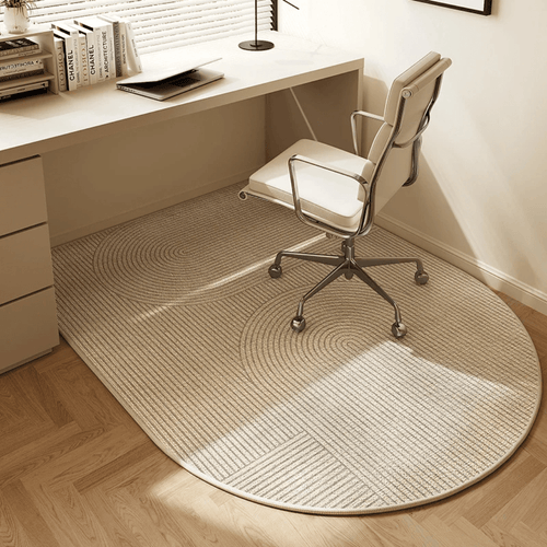 Round beige rug on a wooden floor in front of a desk with a chair.