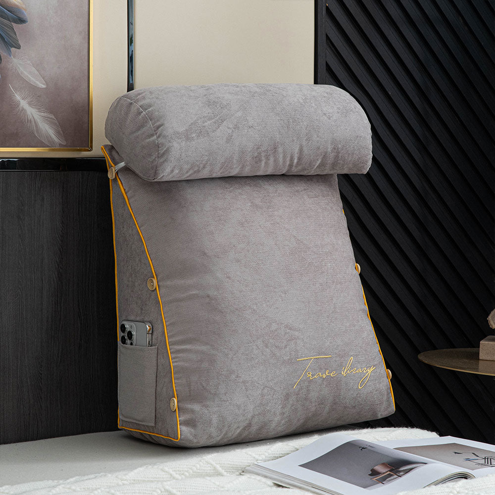 Gray wedge-shaped pillow with yellow accents on a surface, with a magazine open in front.