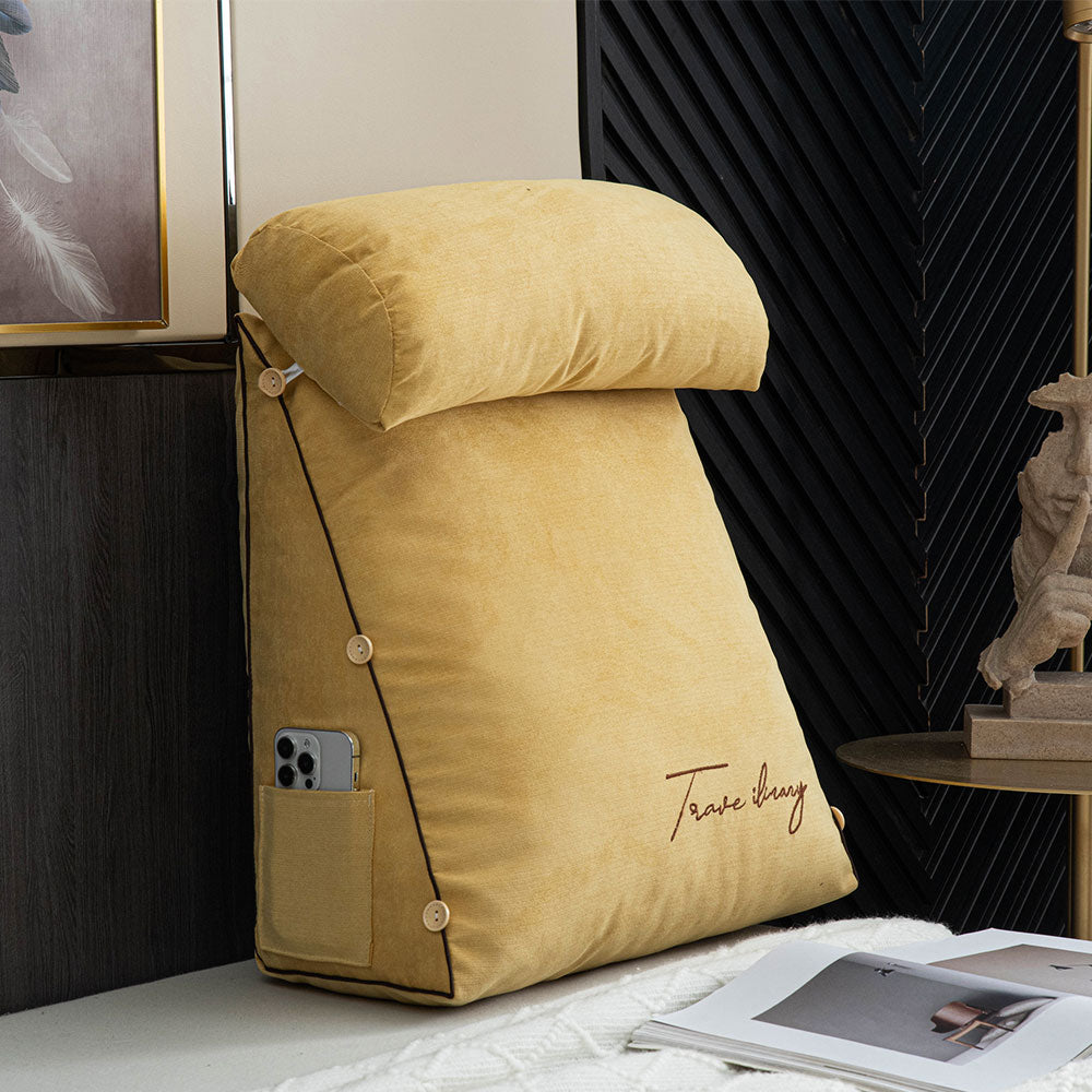 Yellow wedge-shaped pillow with a pocket on a bed next to a magazine