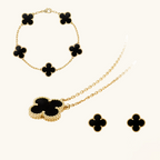 Gold jewelry set with black clover-shaped stones on a white background