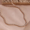 Rose gold necklace with clear stones on a beige fabric background
