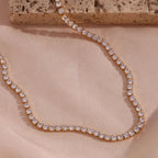 Rose gold necklace with clear stones on a beige fabric background