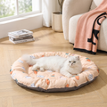 Cat lying on a round pet bed with cartoon designs in a cozy living room.