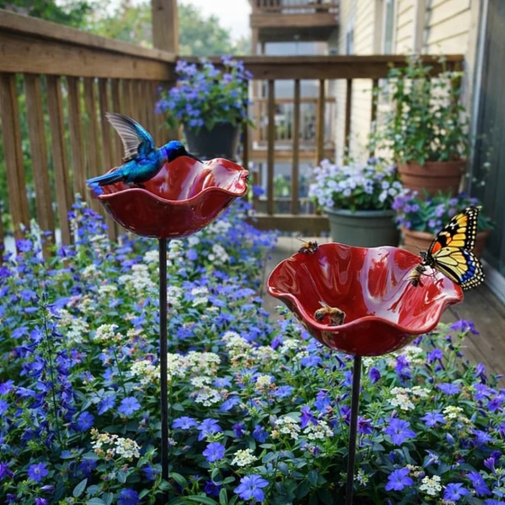 Two red flower-shaped bird baths with decorative elements in a garden setting.