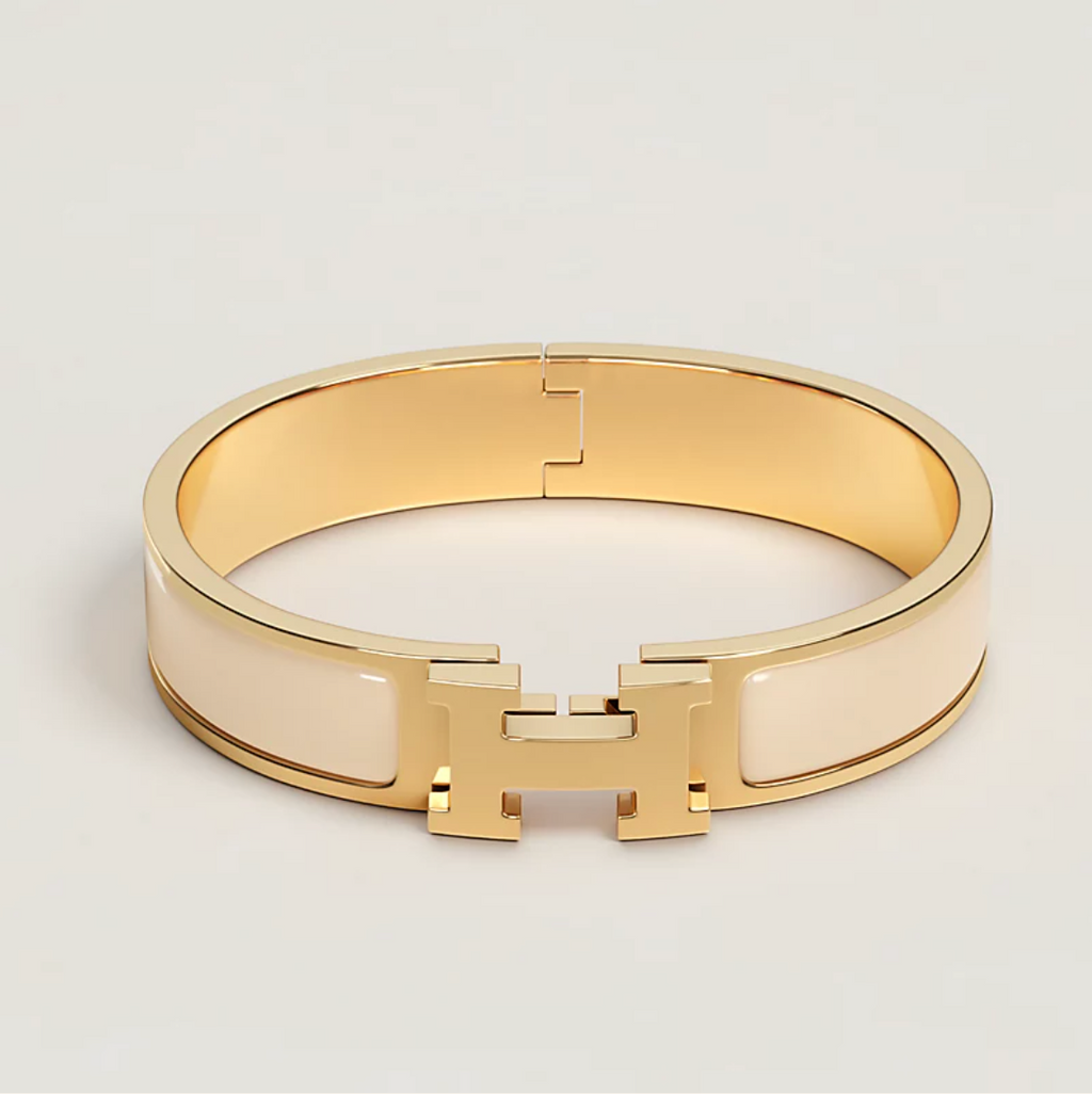 Gold bracelet with a brand logo on a light gray background