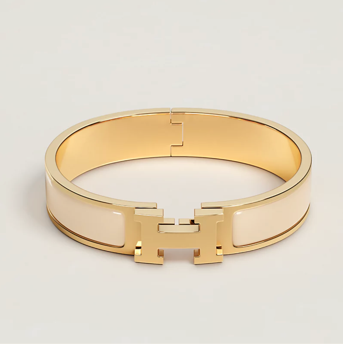 Gold bracelet with a brand logo on a light gray background