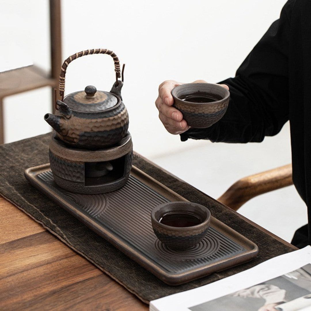 Tea set with teapot, cups, and tray on a wooden table.