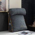 Gray wedge pillow with gold accents on a bed next to an open magazine.