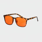 Sunglasses with orange lenses and tortoiseshell frame on a light gray background