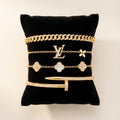 Gold jewelry on a black cushion with a visible brand logo
