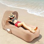 Person relaxing on a beige inflatable beach chair by the ocean.