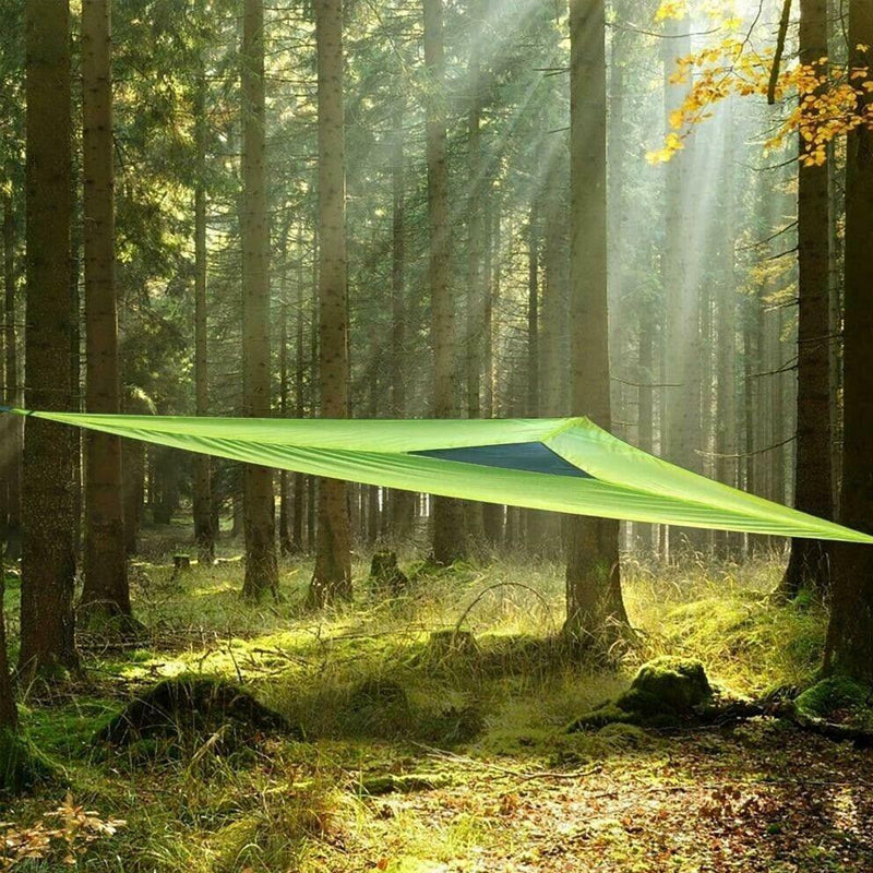 Green tarp set up in a forest with sunlight filtering through the trees