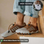 Person wearing brown shoes with a wide toe box feature, sitting on a wooden stool.