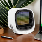 Small white fan on a desk with a laptop and remote control in the background