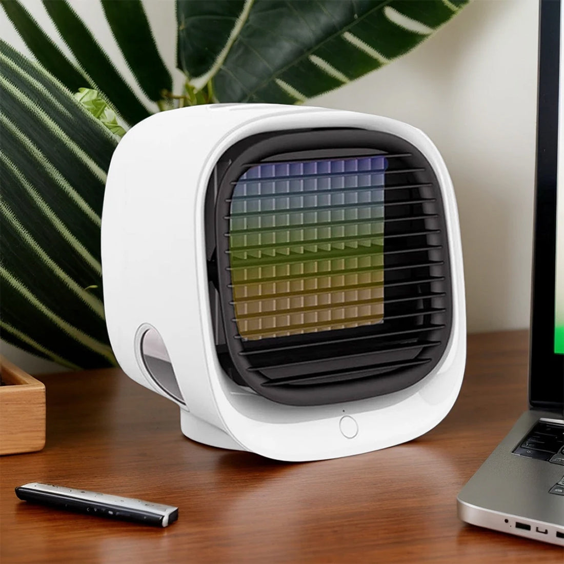 Small white fan on a desk with a laptop and remote control in the background