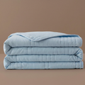 Folded light blue comforter on a brown background