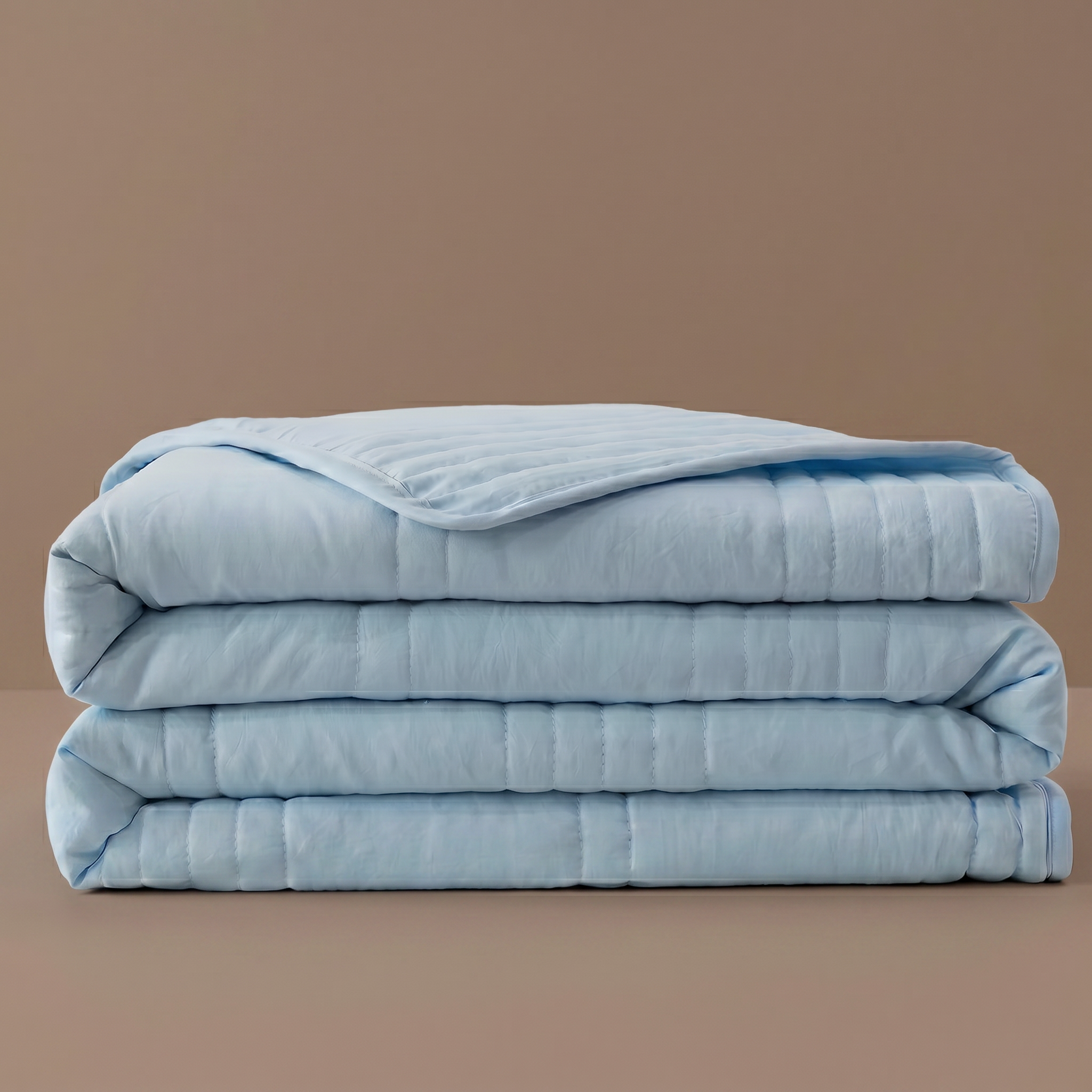 Folded light blue comforter on a brown background