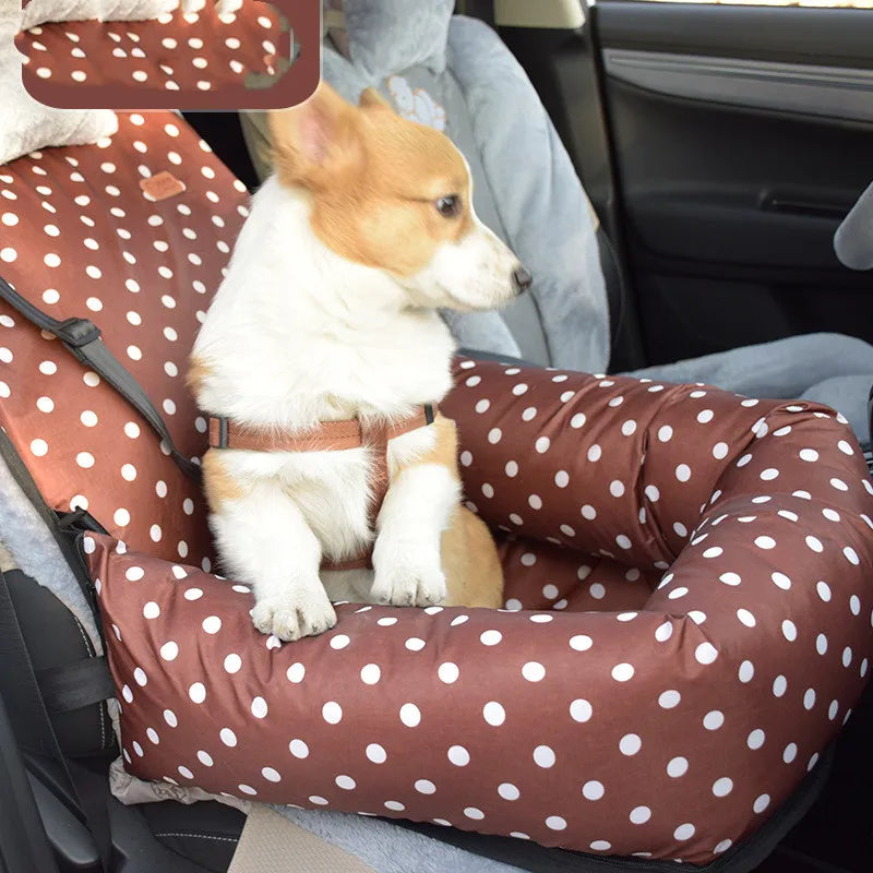 Dog sitting on a brown polka dot car seat cover in a vehicle.