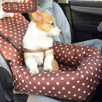 Dog sitting on a brown polka dot car seat cover in a vehicle.
