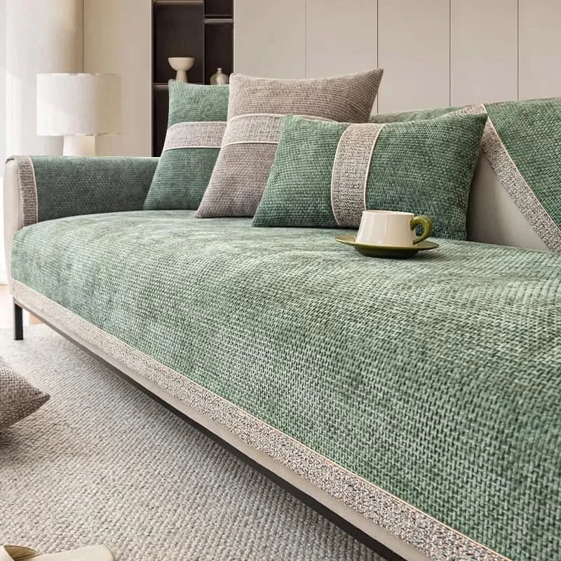 Green sofa with cushions and a cup on a light gray carpet in a room.