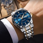 Luxury watch with blue dial and silver and gold bracelet on a wrist.
