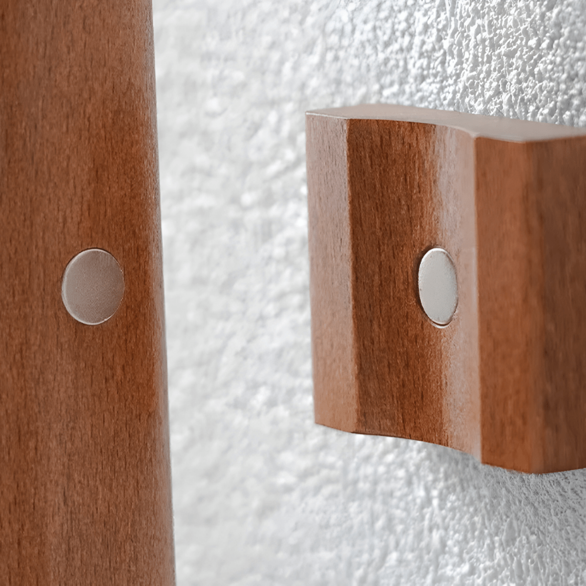 Wooden wall hooks with metal circular plates on a textured white background