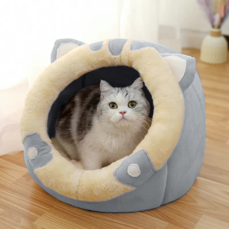 Cat inside a round, plush pet bed with a beige interior and gray exterior on a wooden floor.