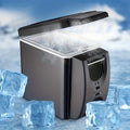 Portable ice maker with ice cubes on a snowy background