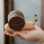 Wooden snail figurine held in a hand with a blurred background