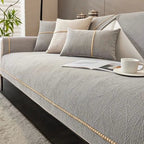 Gray sofa with decorative pillows and a cup on a saucer in a living room setting.
