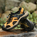 Pair of outdoor sandals with black and yellow accents on a natural rock background