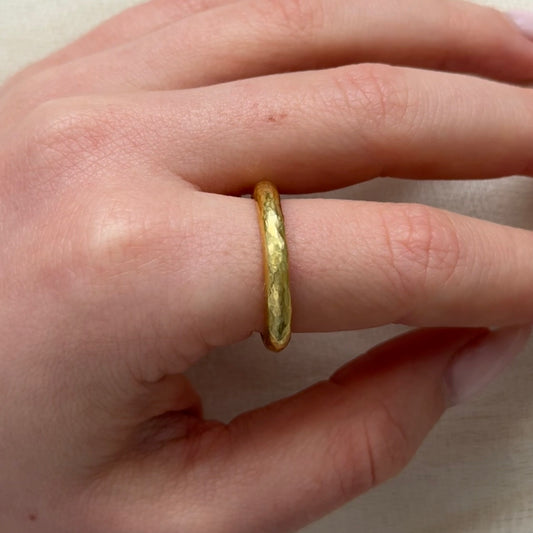 22ct Gold ring on a finger against a neutral background