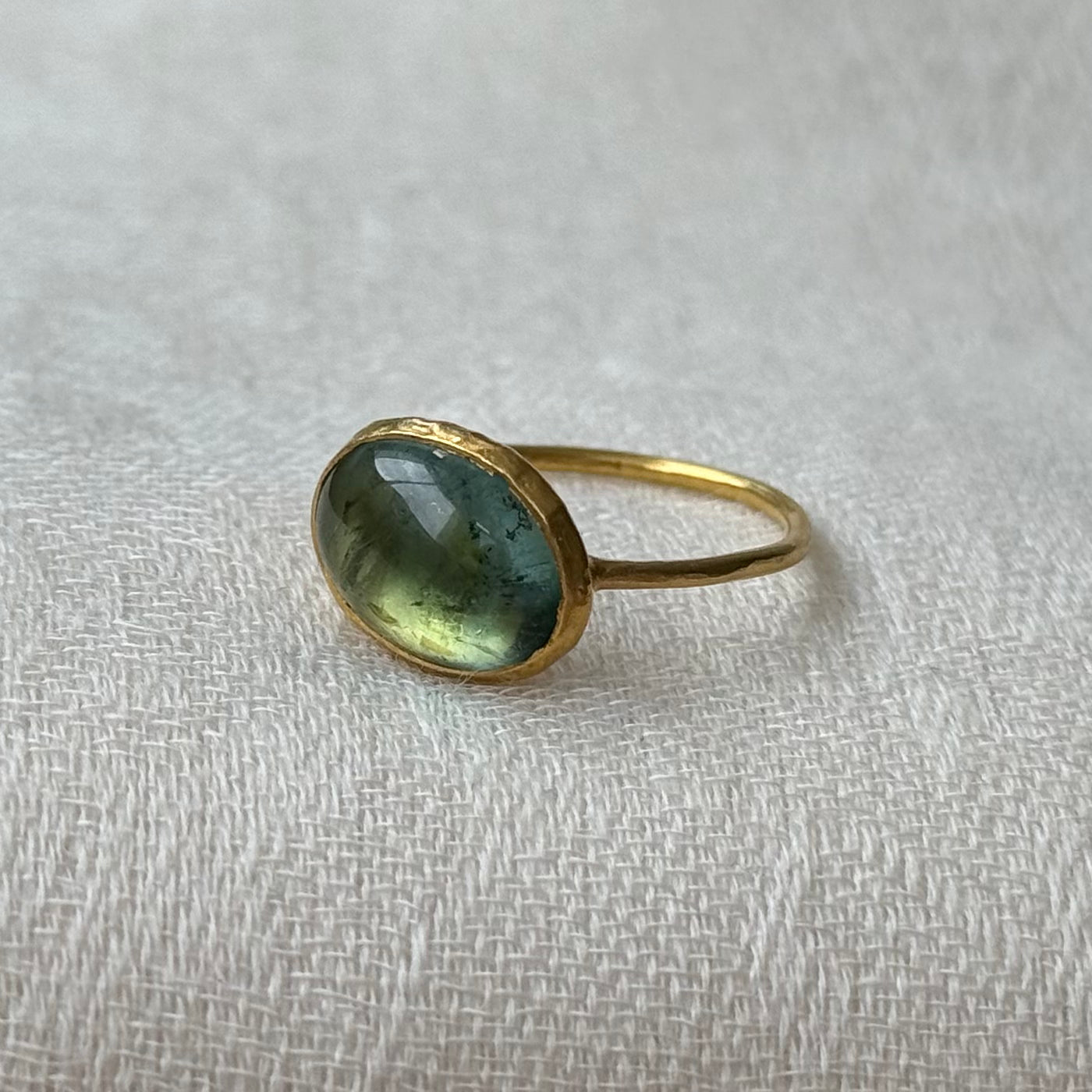 22ct solid Gold ring with a green tourmaline gemstone on a textured white background