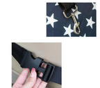 Black strap with gold clasp on a navy background with white stars, close-up of black strap buckle.