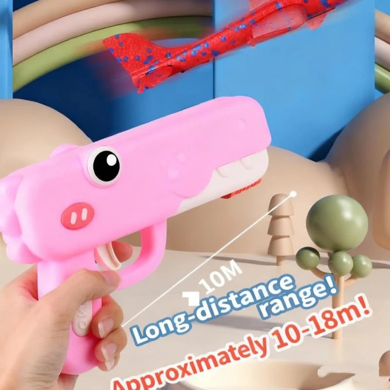 Pink toy gun with a cartoon pig design, held by a hand, with text indicating long-distance range.