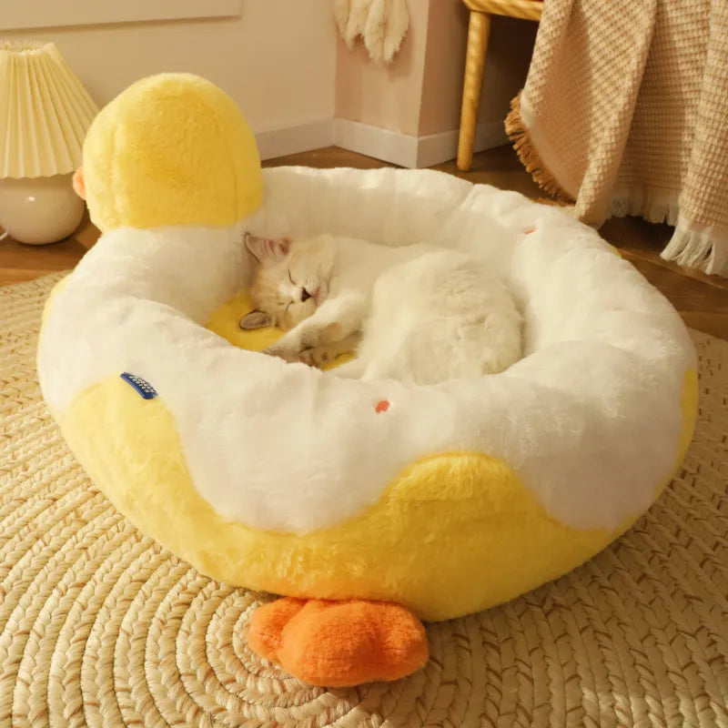 Cat lying on a yellow duck-shaped pet bed in a cozy room.