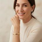 Woman wearing gold jewelry against a neutral background