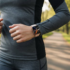 Person wearing a smartwatch outdoors on a blurred natural background